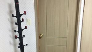 A room with a wooden door, a coat rack with hooks, and a light switch on the wall. - One bedroom near Ansan Station (Ansanshi)