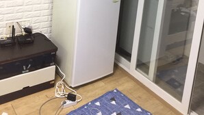 A compact kitchen with a white refrigerator, a dark wooden cabinet, and a glass door leading to a balcony. - One bedroom near Ansan Station (Ansanshi)