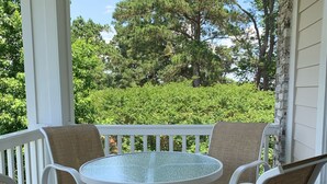 A covered outdoor seating area with a round table and white wicker chairs.