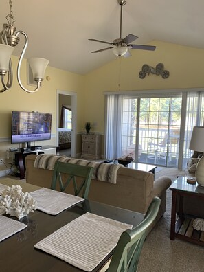 A dining area with a table set for four, a ceiling fan, and a television displaying a message. - Cozy Retreat in Myrtle Beach: On-Site Golf and Pools! Only 1 mile to Beach! (Myrtle Beach)