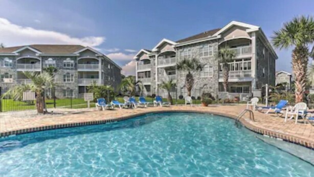 A swimming pool with lounge chairs and a stone building with balconies.