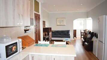 A compact kitchen with a microwave, a dining table, and a sofa in the living area.