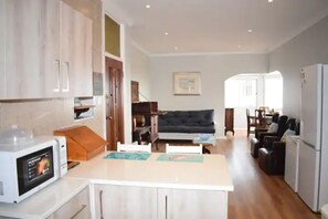 A compact kitchen with a microwave, a dining table, and a sofa in the living area.