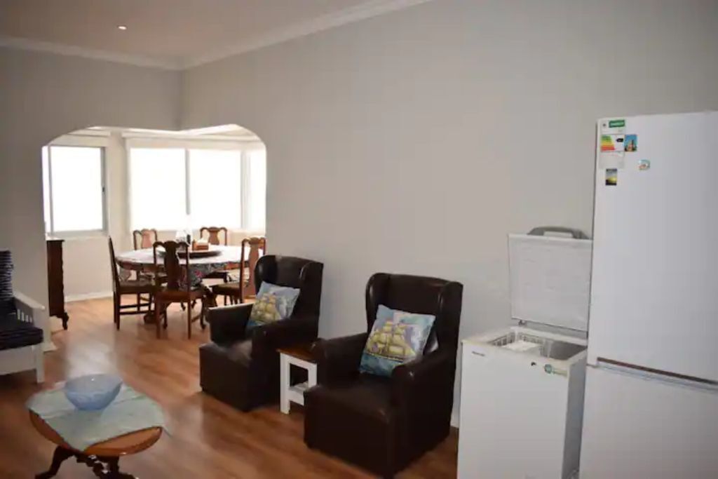 Een woonkamer met een eethoek, een koelkast en een klein tafeltje met een kom.