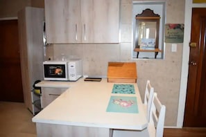 A small kitchen with a microwave, a wooden table, and a few chairs.