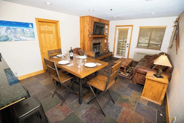 Un área de comedor con una mesa y sillas de madera, una chimenea y un sofá.