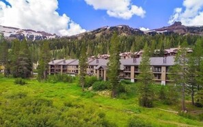 Un hotel con varias edificaciones rodeado de vegetación y montañas al fondo.