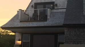 A two-story house with a balcony, a garage, and a white fence.
