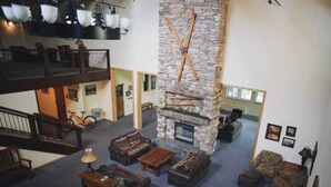 A spacious lobby with a stone fireplace, multiple seating areas, and a balcony.