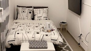 A bedroom with a bed, a TV mounted on the wall, a small bedside table, and a power outlet. - STUDIO hyper-centre/Lyon- Eurexpo/ Parc OL (Décines-Charpieu)