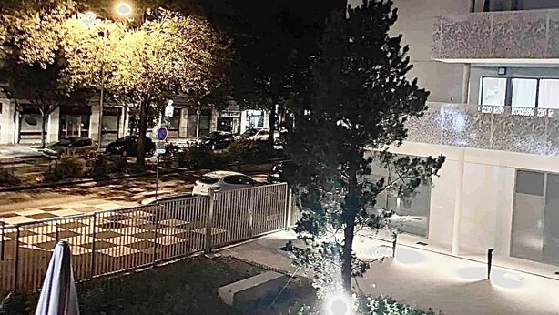 A nighttime view of a courtyard with a tree, a fence, and a building with balconies. - STUDIO hyper-centre/Lyon- Eurexpo/ Parc OL (Décines-Charpieu)