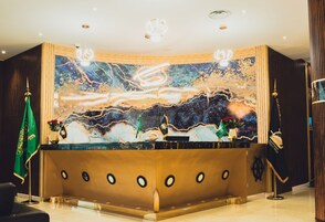 Un mostrador de recepción con fondo de mármol, banderas y una rueda de barco.