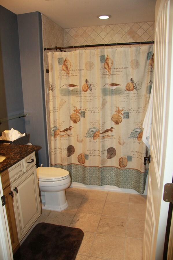 A bathroom with a shower curtain featuring sea creatures, a toilet, and a sink with a towel holder. - Brigantine tri-level house two properties from beach (Brigantine)