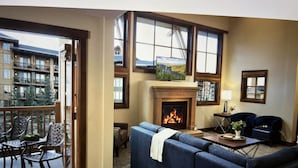 A cozy living room with a fireplace, a sofa, and a balcony with outdoor furniture. - Beautiful Ski in and Ski out Lodge (Park City)