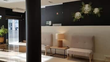 Un vestíbulo con mostrador de recepción, zona de estar y una pared con detalles decorativos.