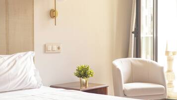 Habitación de hotel con cama, una silla, lámpara de pared y ventana con cortinas.