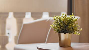 A round table with a potted plant, a beige sofa, and a view of a building with balconies.