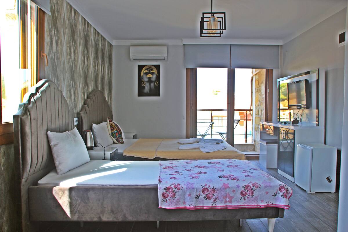 A bedroom with a bed, a desk, a television, and a balcony.
