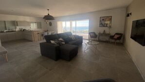 A spacious living area with a sofa, a coffee table, and a view of the outdoors. - House (Cargèse)