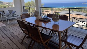 A wooden deck with a table and chairs, overlooking a coastal view. - House (Cargèse)