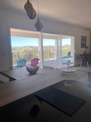 A modern dining area with a large table, chairs, and pendant lights.