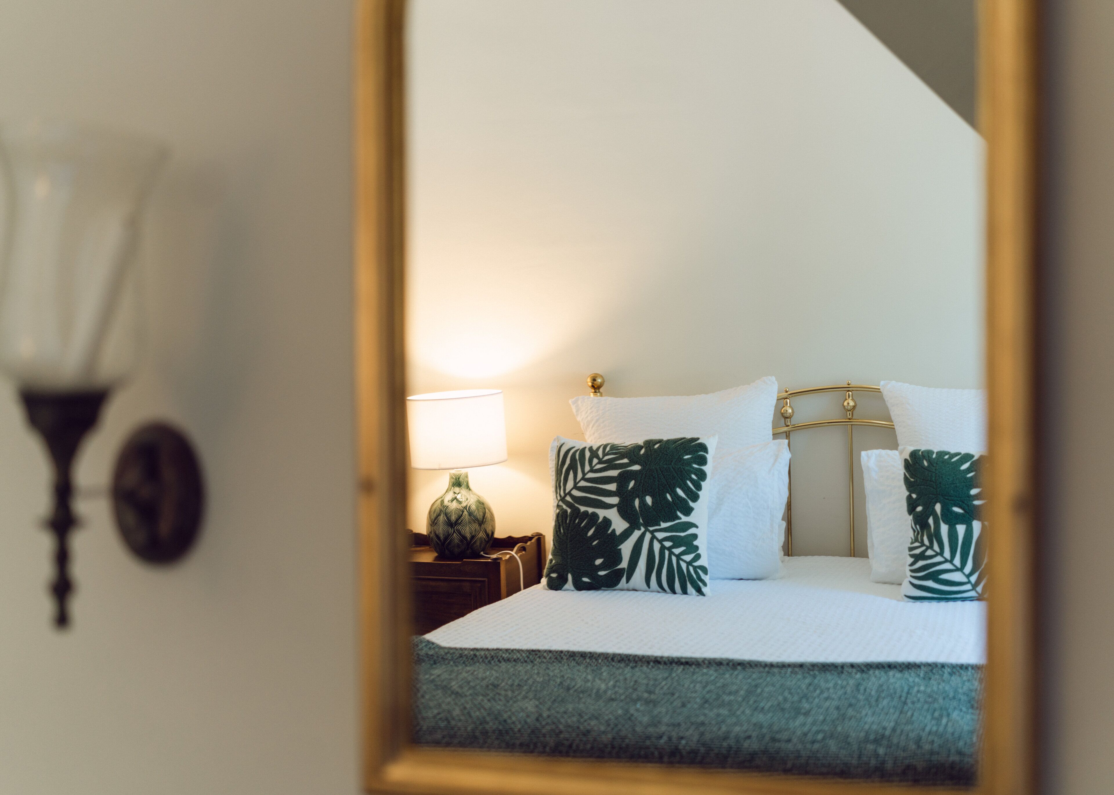 Une chambre à coucher avec un lit, des oreillers, une lampe et une table de chevet.