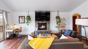 Ein gemütliches Wohnzimmer mit Kamin, einer Couch, einem Couchtisch und einem Fernseher.
