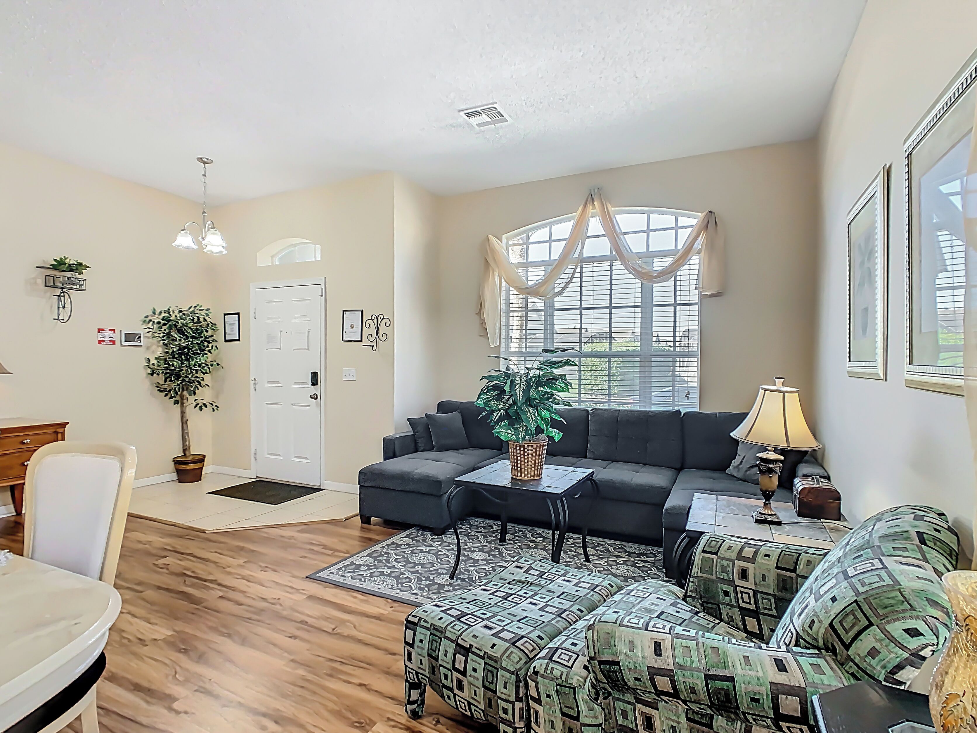 A living room with a sofa, armchair, and a dining area with a table and chairs.