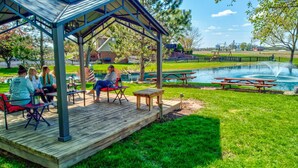 A covered outdoor seating area with picnic tables and a pond. - Peaceful 2BR Farm Stay - 10 Min To Grand Park (Sheridan)