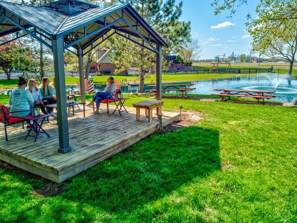 A covered outdoor seating area with picnic tables and a pond. - Peaceful 2BR Farm Stay - 10 Min To Grand Park (Sheridan)
