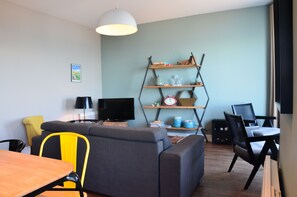 Ein modernes Wohnzimmer mit einer Couch, einem Esstisch, einem Fernseher und einem Bücherregal.
