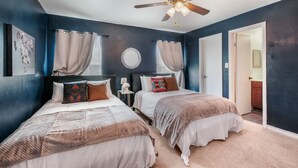 A bedroom with two beds, a ceiling fan, and a door leading to a bathroom. - SP1  20% OFF New 3BR Home for Families or Large Groups 5-mins from Methodist (San Antonio)