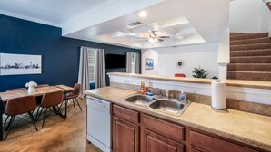 A modern kitchen with a built-in dishwasher, a double sink, and a dining area with a wooden table and chairs. - SP1  20% OFF New 3BR Home for Families or Large Groups 5-mins from Methodist (San Antonio)