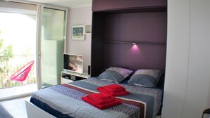 Un dormitorio moderno con una cama grande, un televisor y una puerta corrediza al exterior.