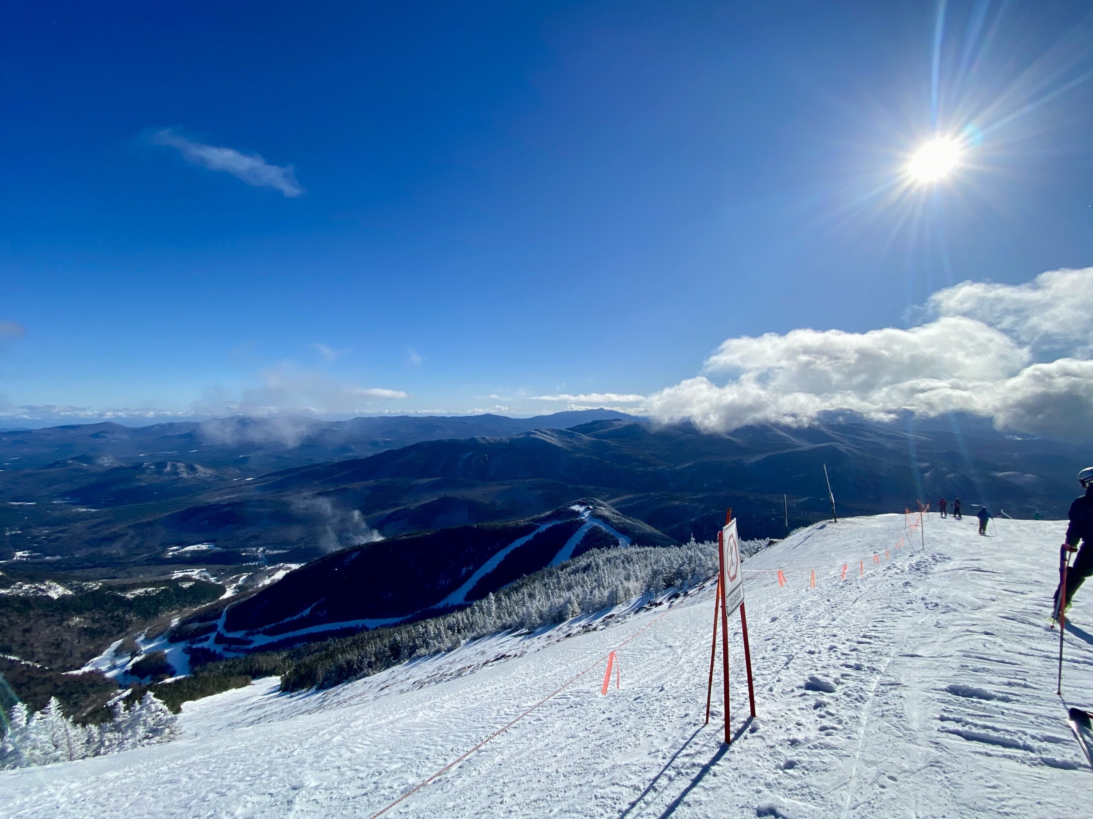 A snowy ski slope with a clear sky and distant mountains.