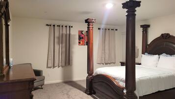 A bedroom with a four-poster bed, a desk, and a chair.