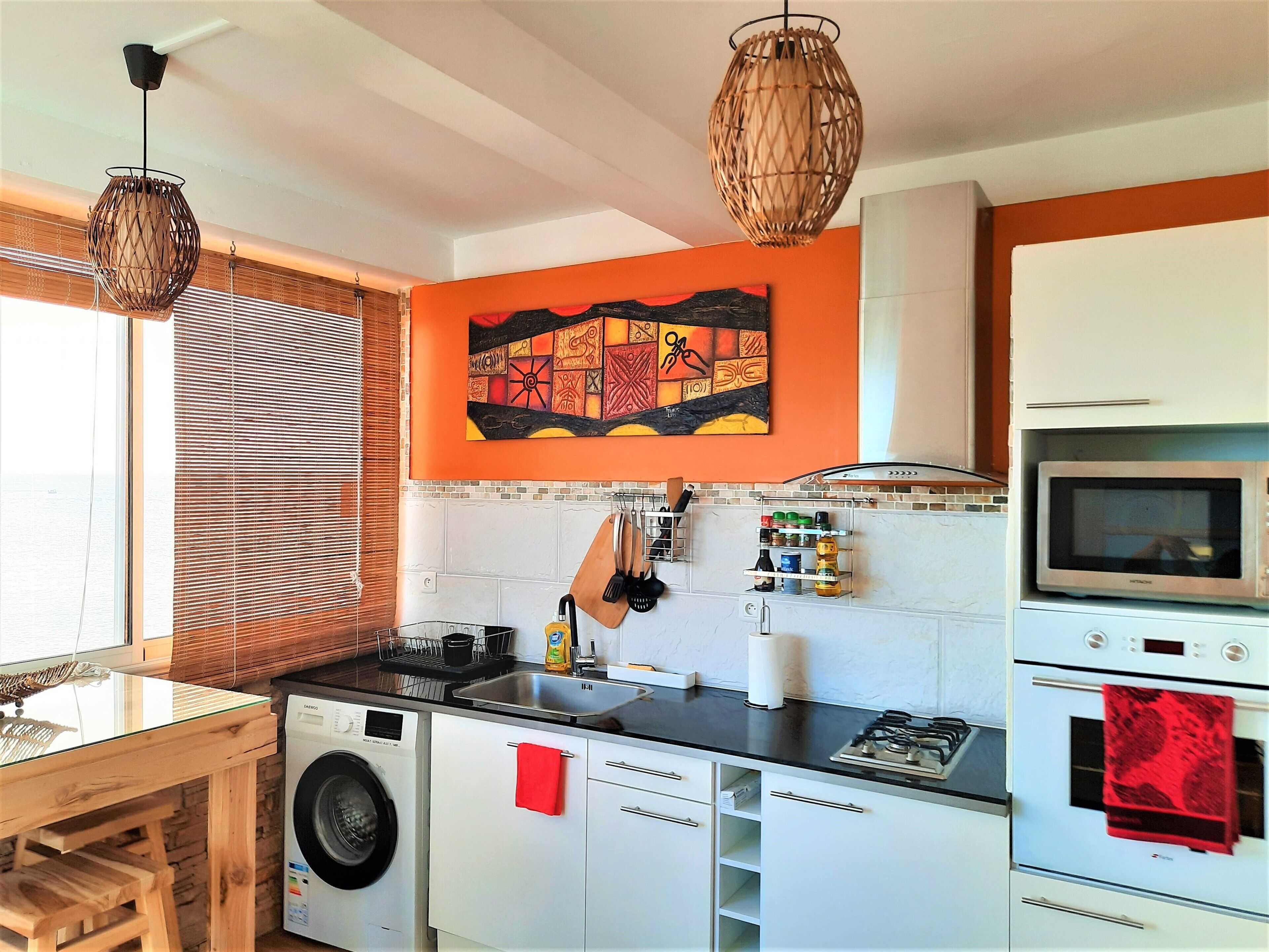 Une cuisine moderne équipée d’un lave-linge, d’un four à micro-ondes et d’une cuisinière à gaz.