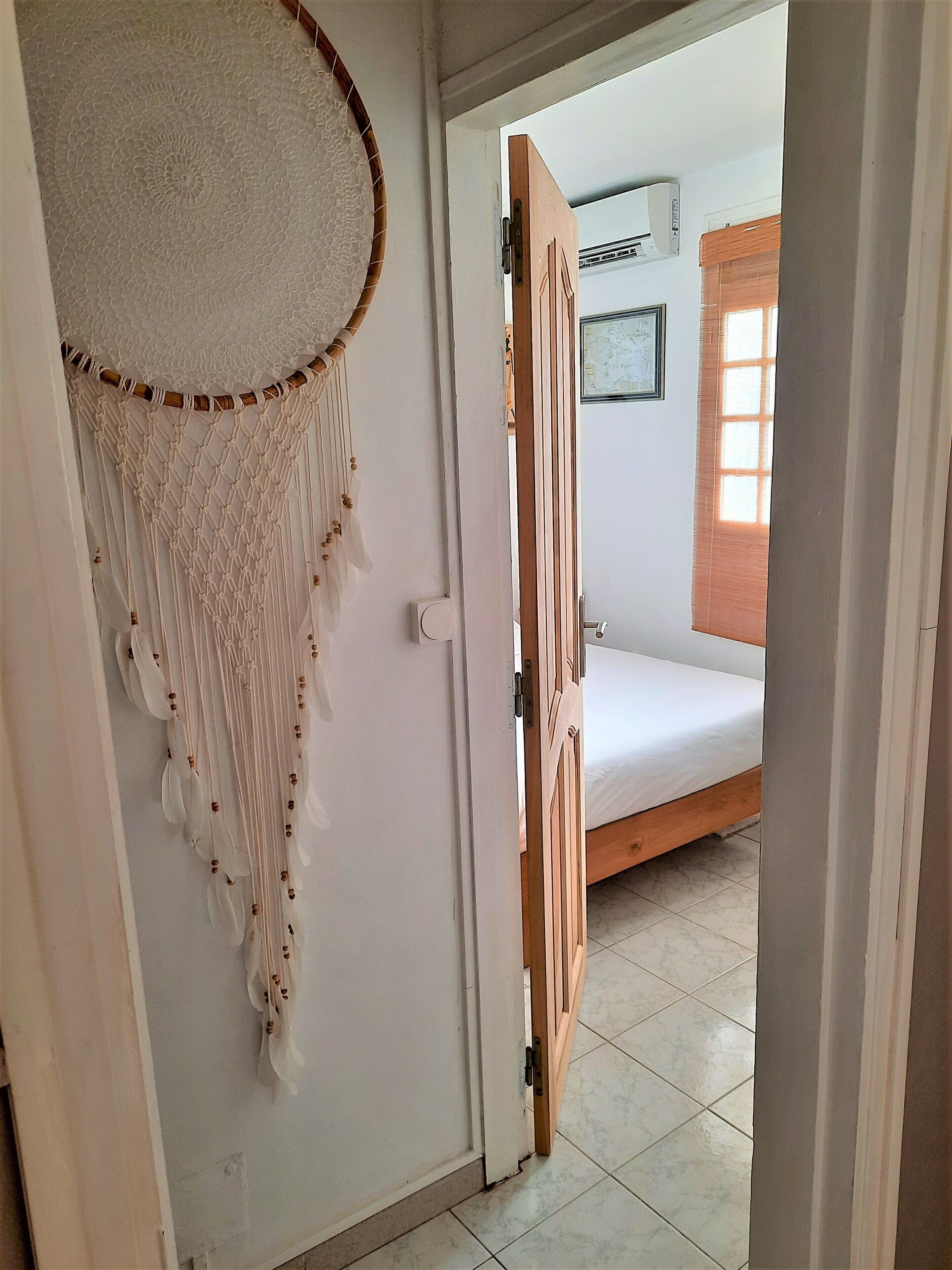 Une chambre avec un lit, un climatiseur fixé au mur et une décoration murale en macramé.