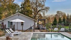 A swimming pool with lounge chairs, a covered patio, and a small house with a staircase. - Healdsburg Homestead with Pool, Hot Tub and Tastings Included (Healdsburg)