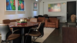 Un comedor moderno con una mesa redonda, sillas de cuero marrón y cuadros abstractos en las paredes.