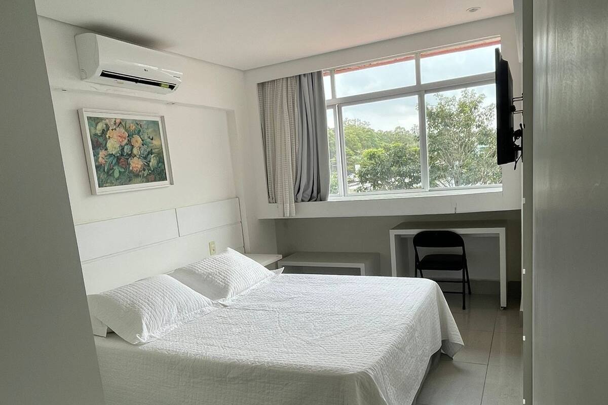 A bedroom with a bed, a desk, and a chair.