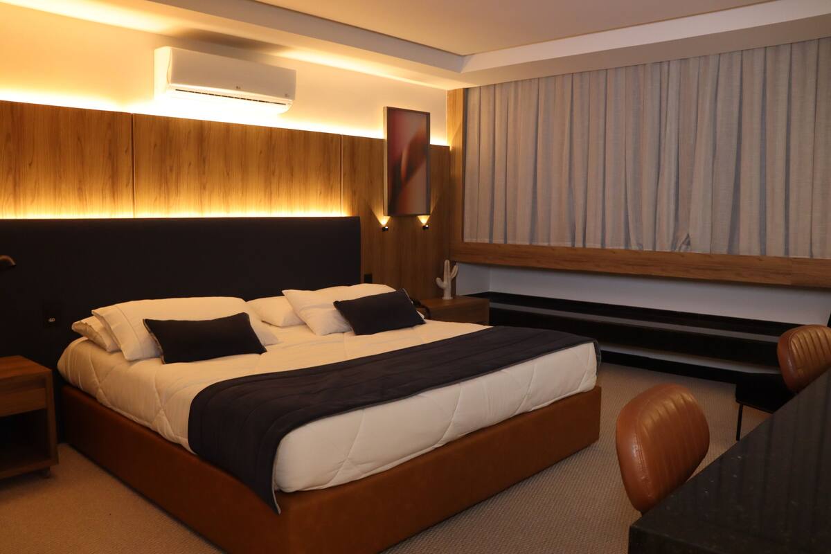 A modern hotel room with a large bed, bedside tables, a desk, and a chair.