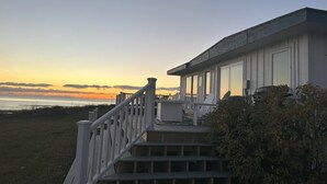 Una casa frente al mar con una escalera que lleva a una terraza con vistas al océano.