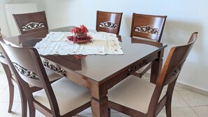 Una mesa de comedor con mantel de encaje, rodeada de sillas de madera con detalles tallados.