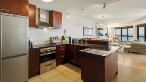 A modern kitchen with stainless steel appliances, wooden cabinets, and a large island. - Beachfront Luxury 1,300 Sq Ft, Workspace, Air Con & False Bay Views (Cape Town)