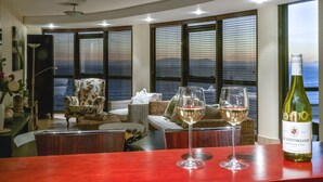 A room with a view of the ocean, a bottle of wine, and two glasses on a table. - Beachfront Luxury 1,300 Sq Ft, Workspace, Air Con & False Bay Views (Cape Town)