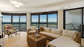 A modern living room with a large panoramic window, a sofa, a chair, and a coffee table. - Beachfront Luxury 1,300 Sq Ft, Workspace, Air Con & False Bay Views (Cape Town)