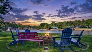 Un espacio al aire libre junto al lago con sillas Adirondack y una chimenea.