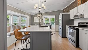 Una cocina moderna con una isla central, armarios blancos y un horno empotrado.