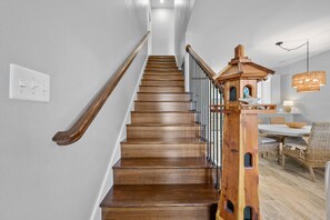 Stairs lead to a cozy dining area with a wicker table and chairs.
